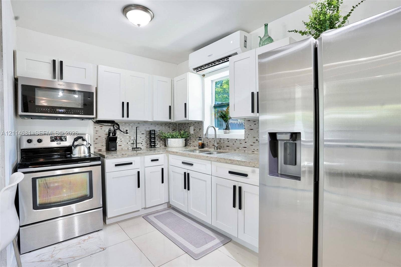 6700 NW 5th Avenue, Miami, FL 33150 Kitchen featuring white shaker-style cabinetry with matte black hardware, stone-finish countertops, stainless steel appliances, a mosaic tile backsplash, and polished tile flooring