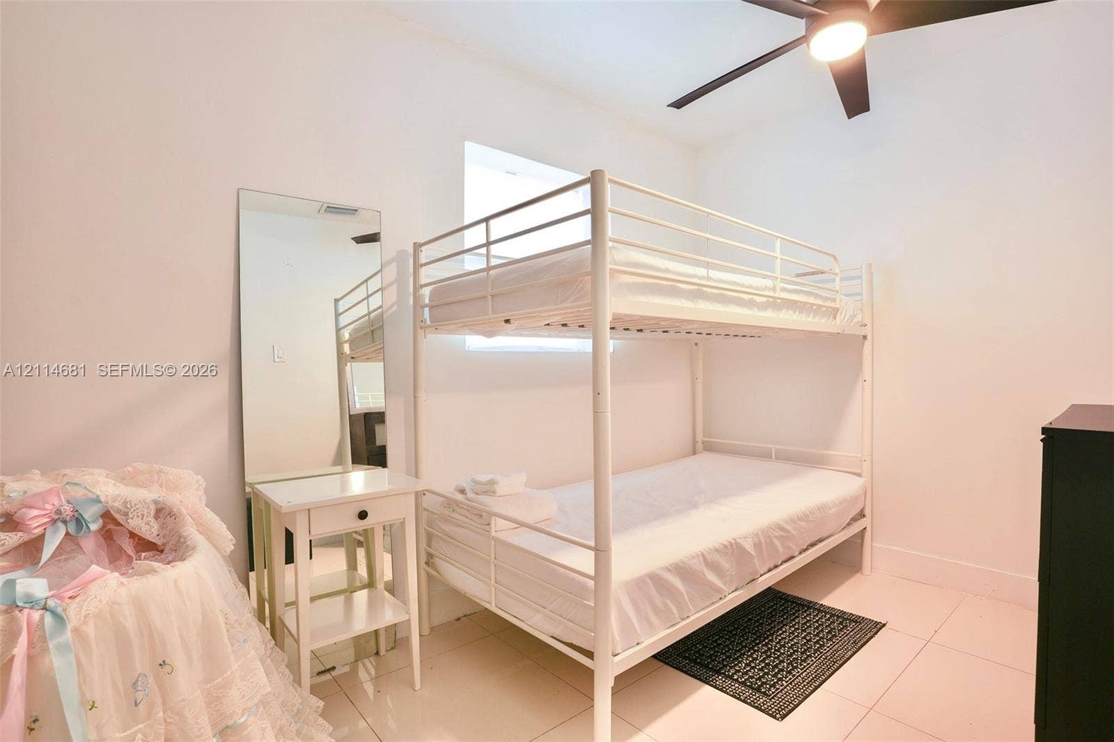 6700 NW 5th Avenue, Miami, FL 33150 Neutral-toned interior featuring large-format tile flooring, a central window with natural light, and an integrated ceiling fan with light fixture