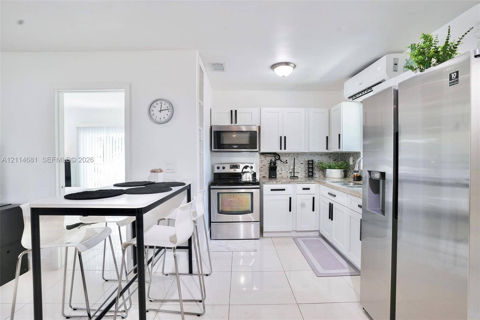 6700 NW 5th Avenue, Miami, FL 33150 Kitchen featuring white shaker-style cabinetry, stainless steel appliances, patterned tile backsplash, neutral stone-finish countertops, and white tile flooring