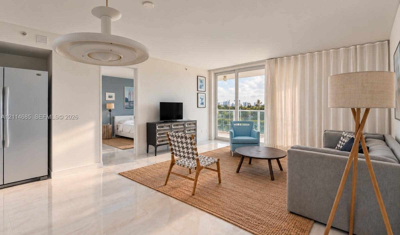1035 West Avenue, #704, Miami Beach, FL 33139 Open-concept living space featuring polished tile flooring, contemporary circular overhead lighting, a floor-to-ceiling sliding glass door, and built-in full-size refrigerator