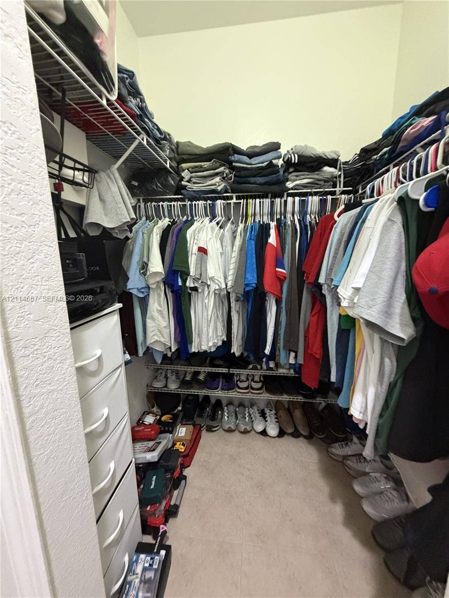 Walk-in storage space featuring tiered wire shelving, built-in vertical drawer cabinetry, and surface-level floor storage