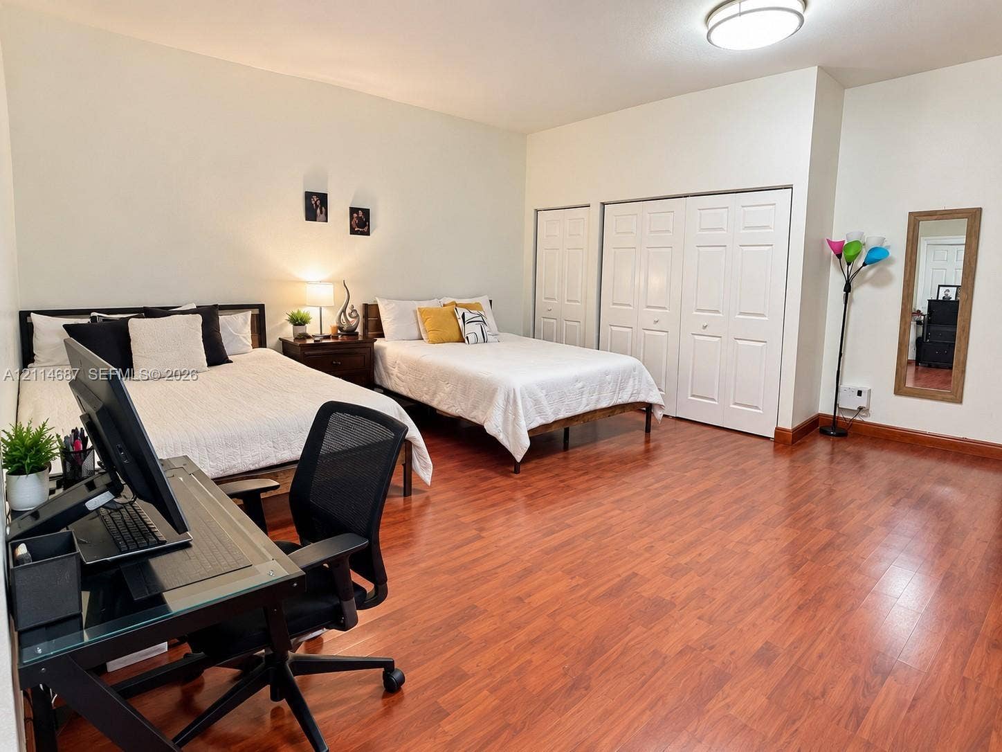 Spacious room featuring wood-finish flooring, recessed ceiling lighting, and double-door closet storage