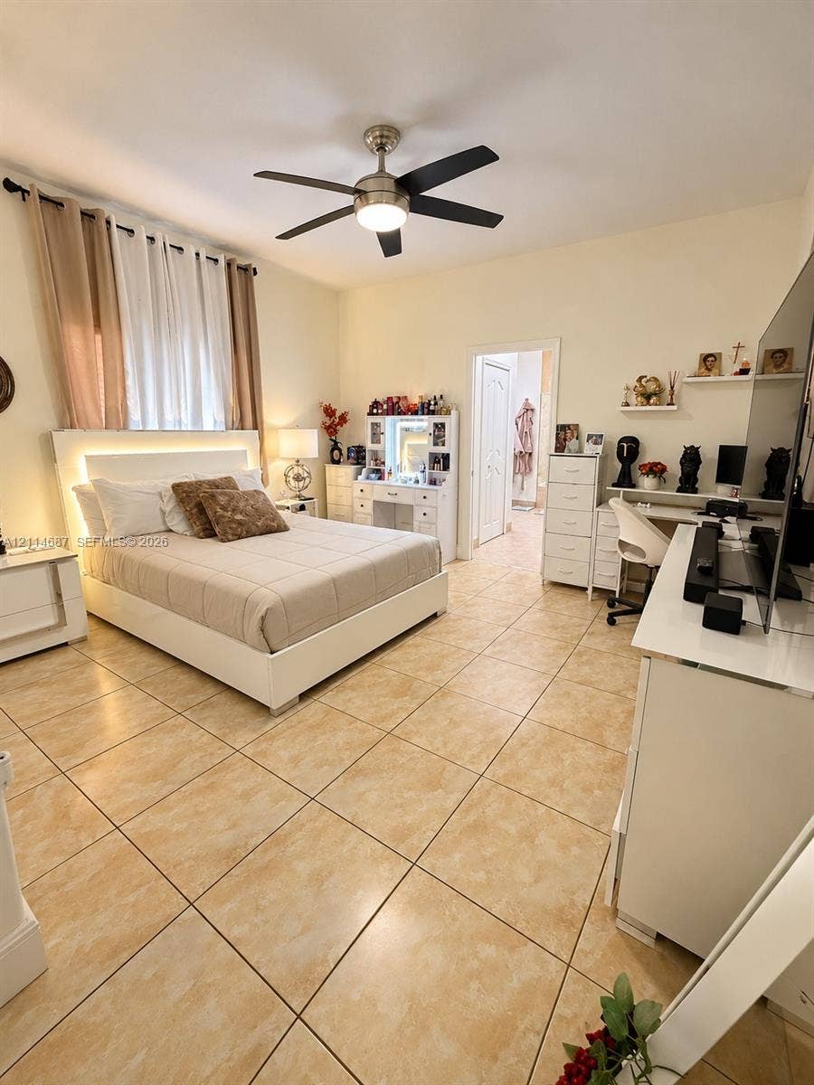Room featuring large-format neutral tile flooring, multi-blade ceiling fan with integrated lighting, and high ceilings
