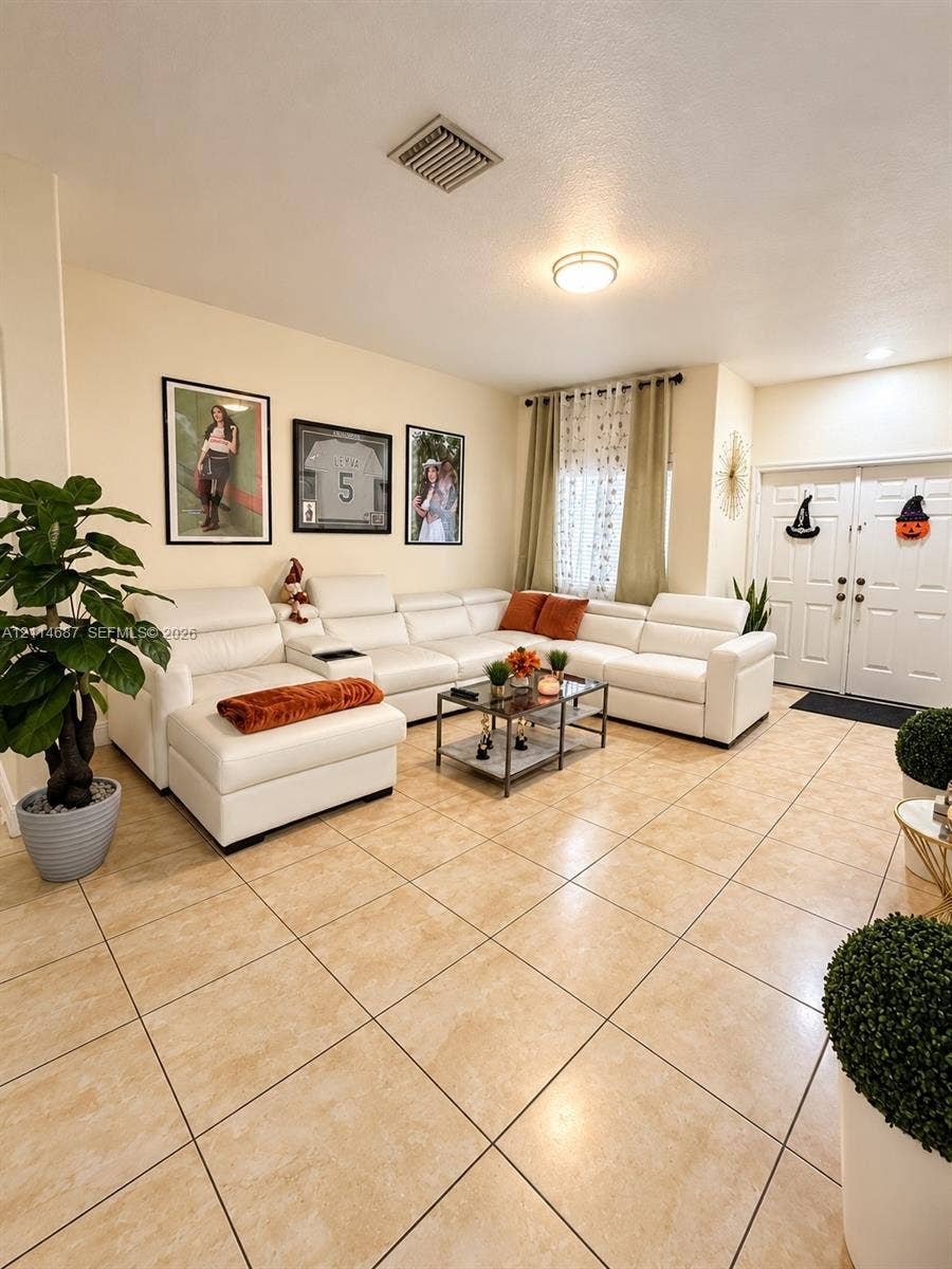 Neutral-toned tile flooring, double-entry doors, and flush-mount ceiling lighting