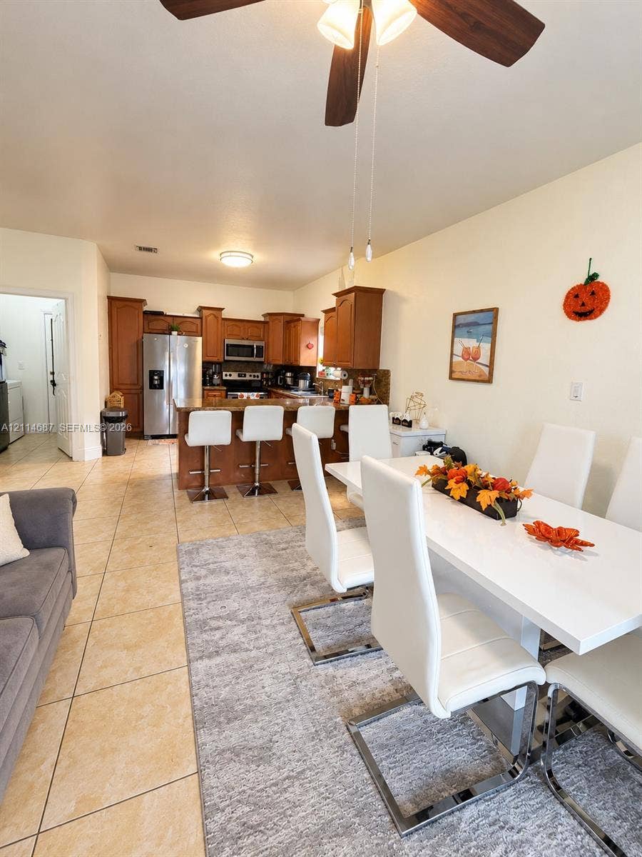 Kitchen featuring wood cabinetry, a breakfast bar, stainless steel appliances, and tile flooring