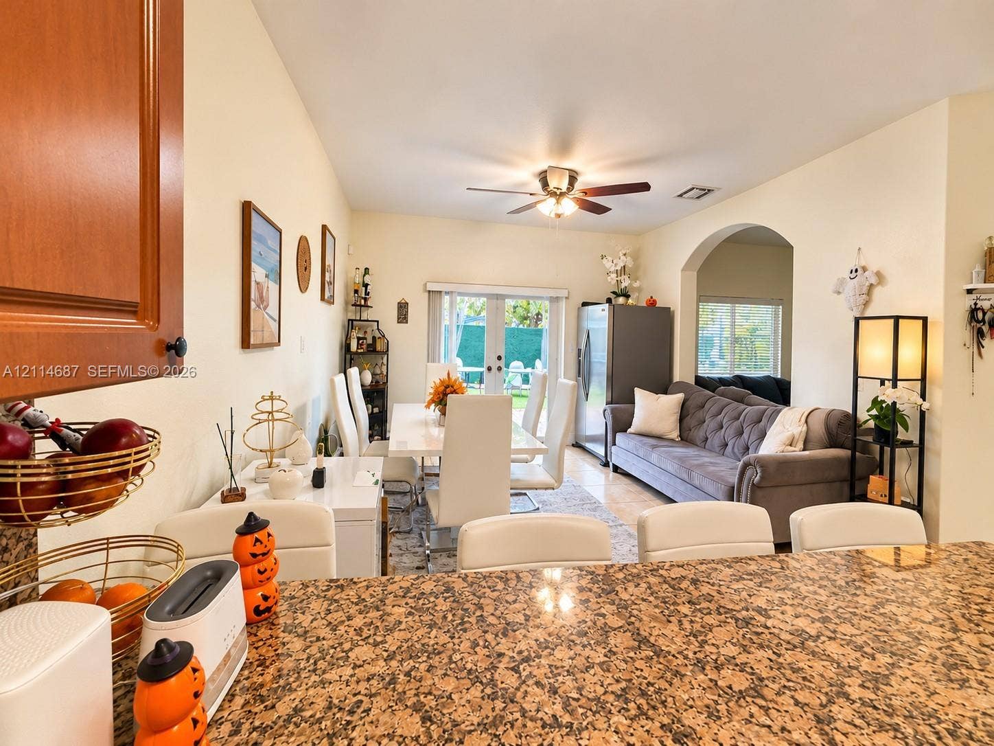 Open-concept interior featuring stone-surface kitchen island, recessed ceiling lighting, a ceiling fan, and a wide arched entryway