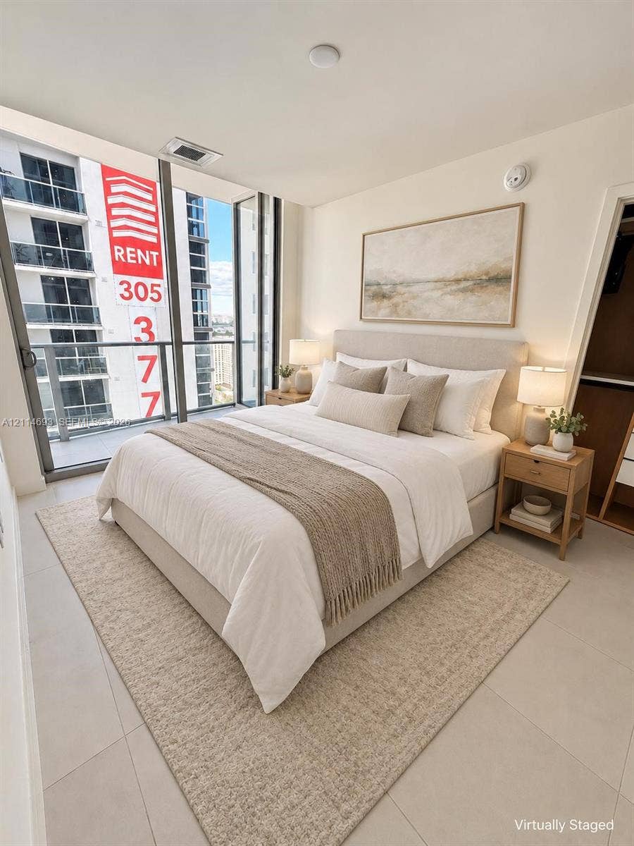 Floor-to-ceiling glass wall, private balcony with metal railing, and neutral tile flooring