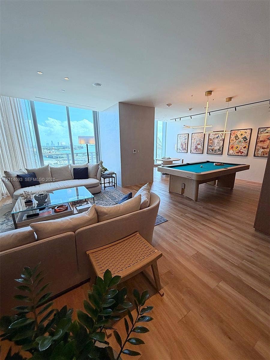 Floor-to-ceiling windows with water and skyline vistas, wood-finish flooring, and recessed ceiling lighting