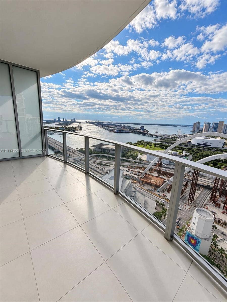 Private balcony featuring large-format ceramic tile flooring, a glass and metal railing system, and floor-to-ceiling glass sliding doors