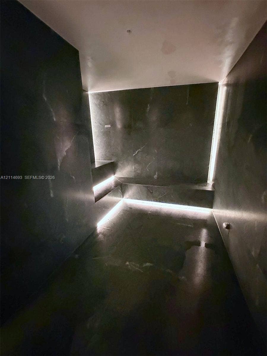 Dark-toned natural stone wall and floor cladding featuring integrated LED cove lighting and built-in stone seating