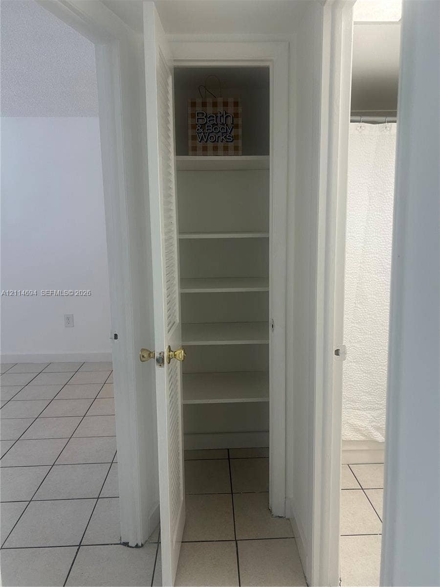 8600 Sunrise Lakes Boulevard, #211, Sunrise, Sunrise, FL 33322 Built-in storage closet featuring louvered door, multiple shelves, and ceramic tile flooring