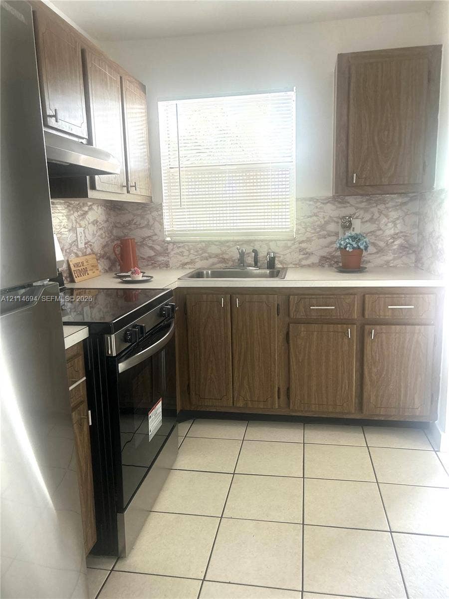 8600 Sunrise Lakes Boulevard, #211, Sunrise, Sunrise, FL 33322 Kitchen featuring wood-finish cabinetry, stainless steel range and refrigerator, stone-patterned backsplash, and ceramic tile flooring