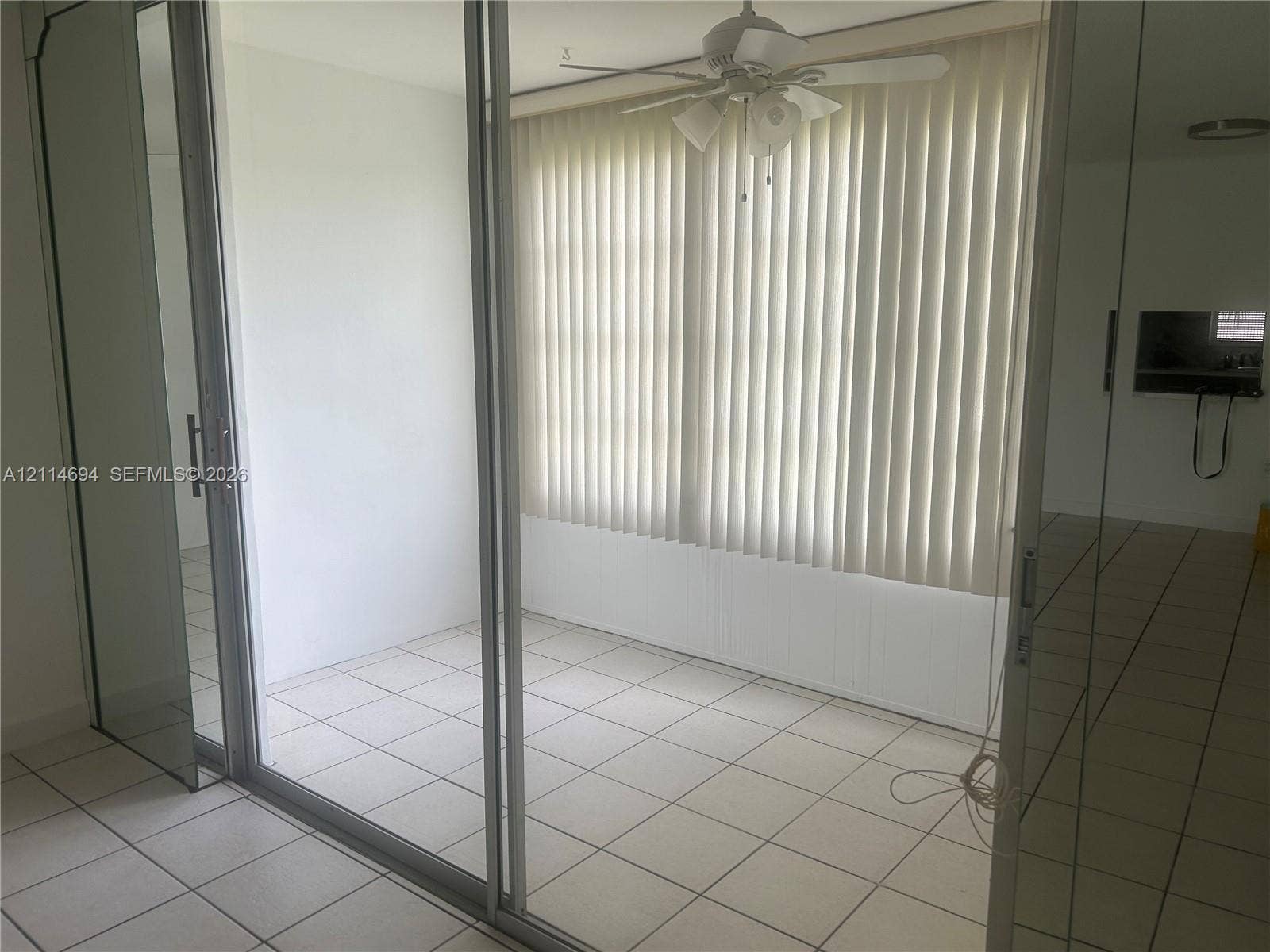 8600 Sunrise Lakes Boulevard, #211, Sunrise, Sunrise, FL 33322 Enclosed space with large-format tile flooring, sliding glass door entry, vertical window blinds, and a white ceiling fan with integrated light fixture