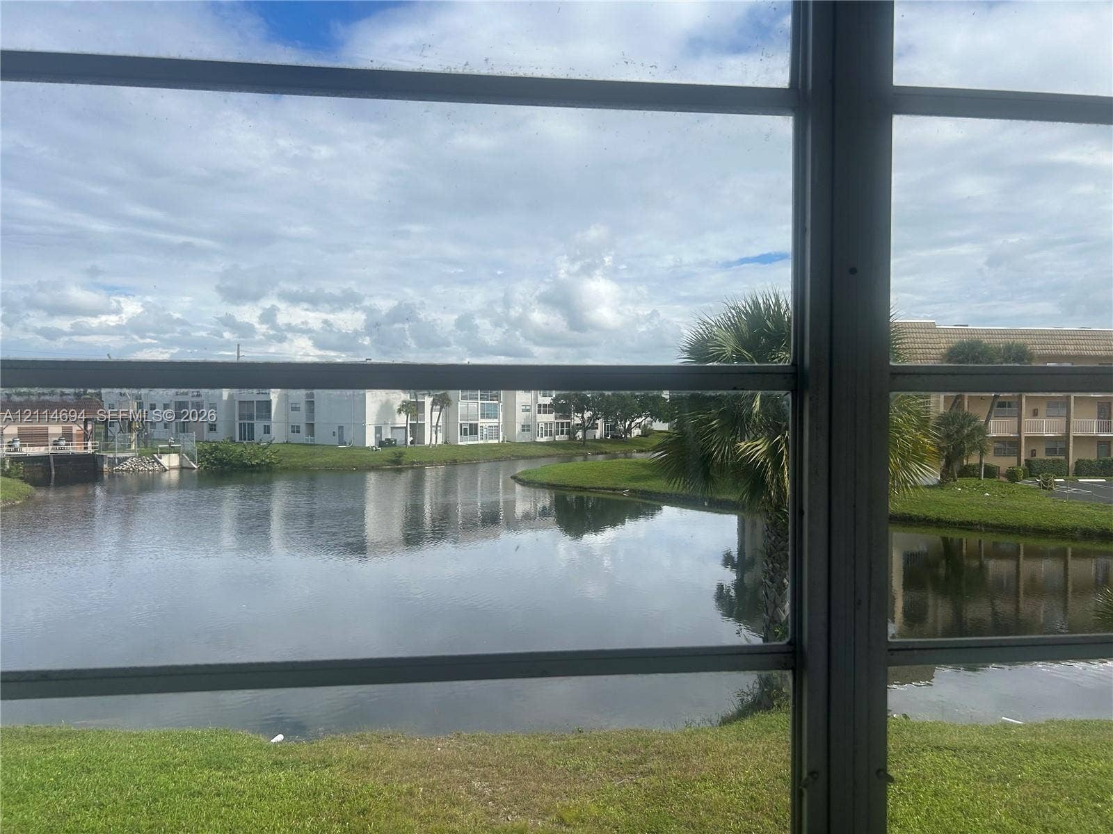 8600 Sunrise Lakes Boulevard, #211, Sunrise, Sunrise, FL 33322 Waterfront exposure featuring a serene pond, manicured turf, and mature palm trees