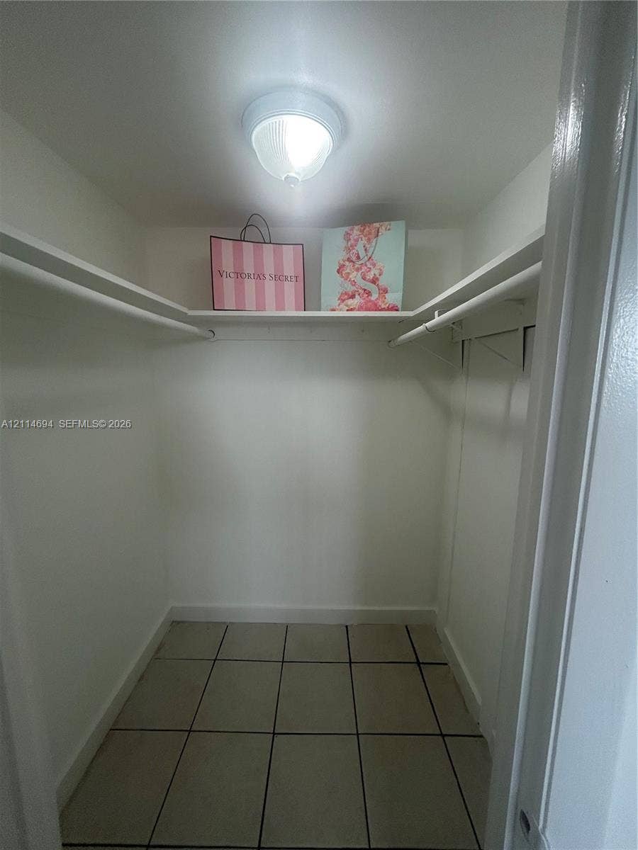 8600 Sunrise Lakes Boulevard, #211, Sunrise, Sunrise, FL 33322 Storage closet featuring ceramic tile flooring, built-in shelving, dual hanging rods, and a ceiling-mounted light fixture