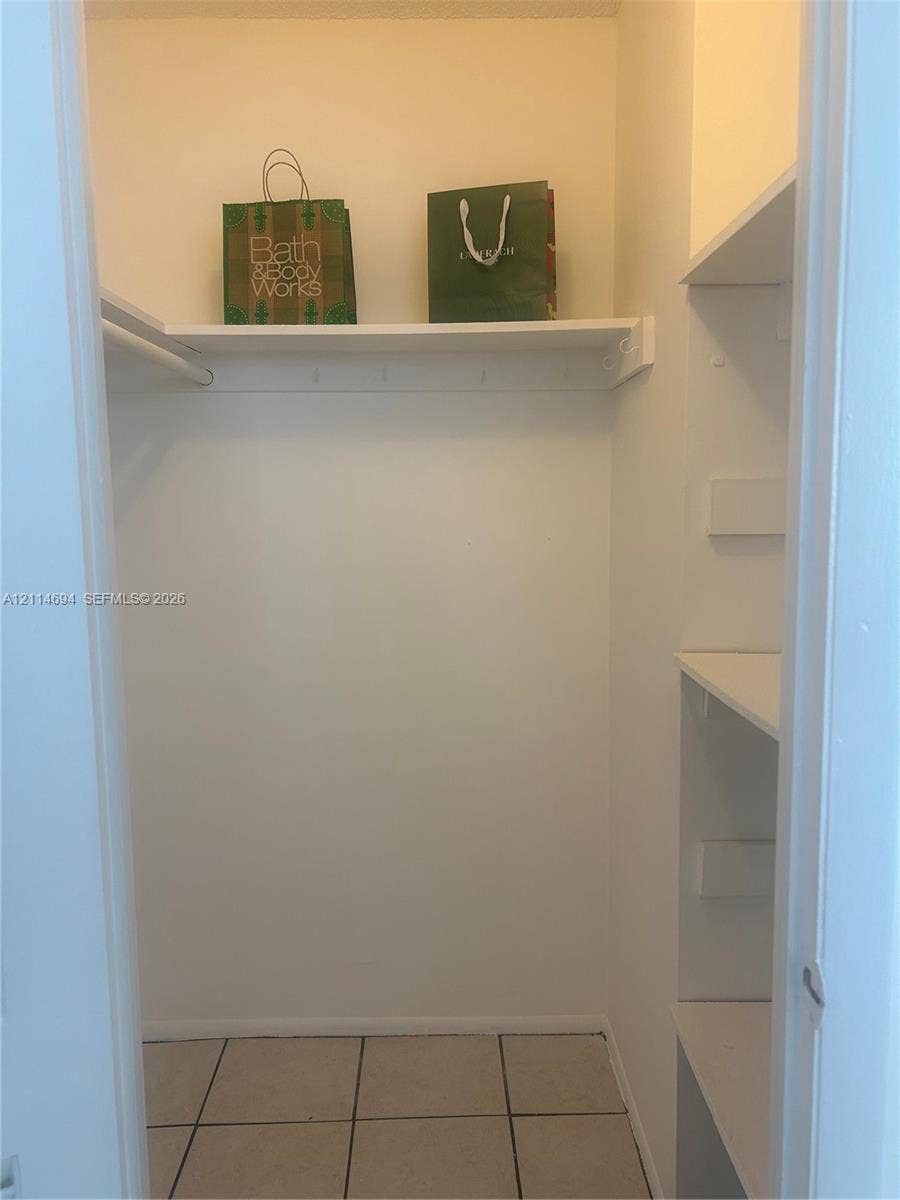 8600 Sunrise Lakes Boulevard, #211, Sunrise, Sunrise, FL 33322 Storage closet featuring tile flooring, built-in shelving, and a hanging rod