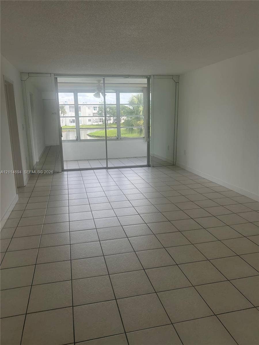 8600 Sunrise Lakes Boulevard, #211, Sunrise, Sunrise, FL 33322 Ceramic tile flooring, mirrored wall accents, and sliding glass doors with exterior access to an enclosed balcony