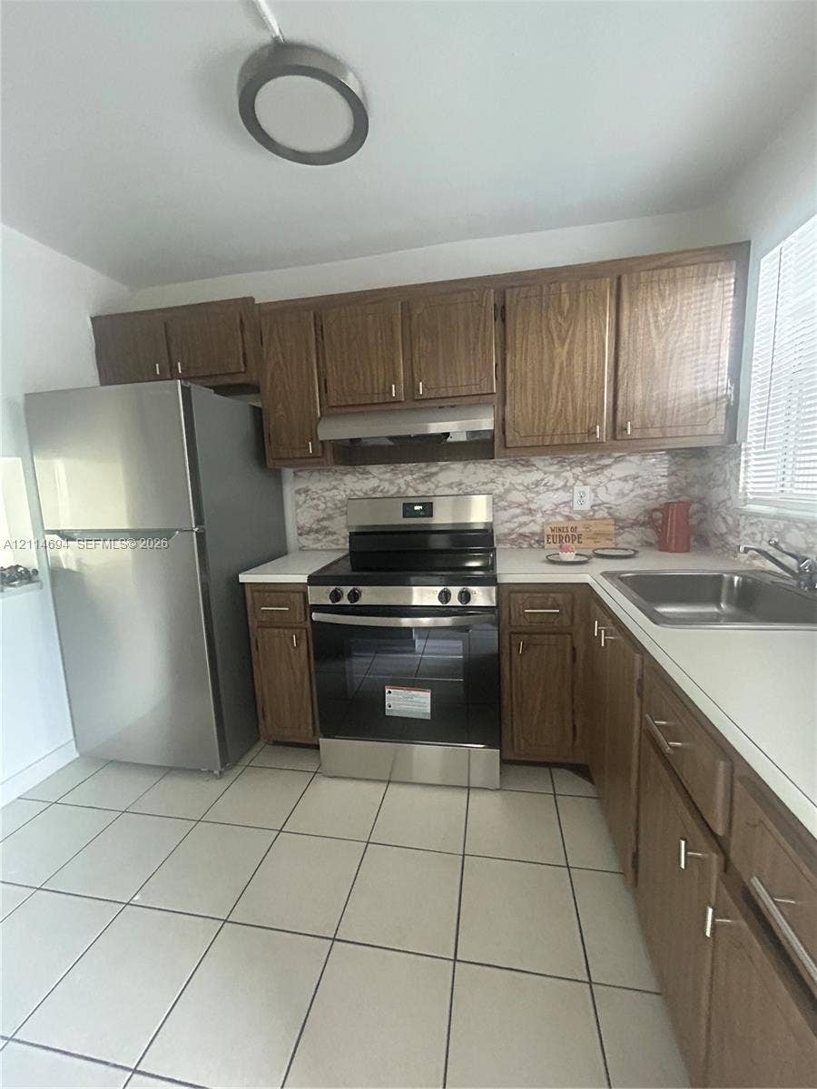 8600 Sunrise Lakes Boulevard, #211, Sunrise, Sunrise, FL 33322 Kitchen featuring wood-finish cabinetry, stainless steel refrigerator and range, tiled flooring, and a stone-finish backsplash