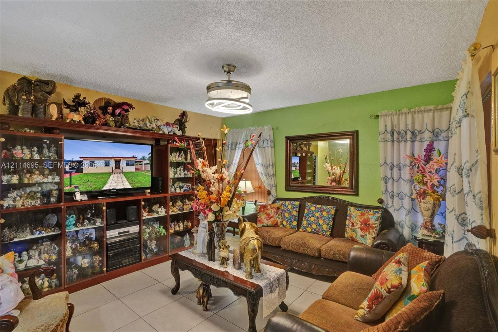 Living area featuring large-format ceramic tile flooring, built-in floor-to-ceiling cabinetry, a modern drum-style ceiling fan with integrated LED lighting, and a framed wall mirror