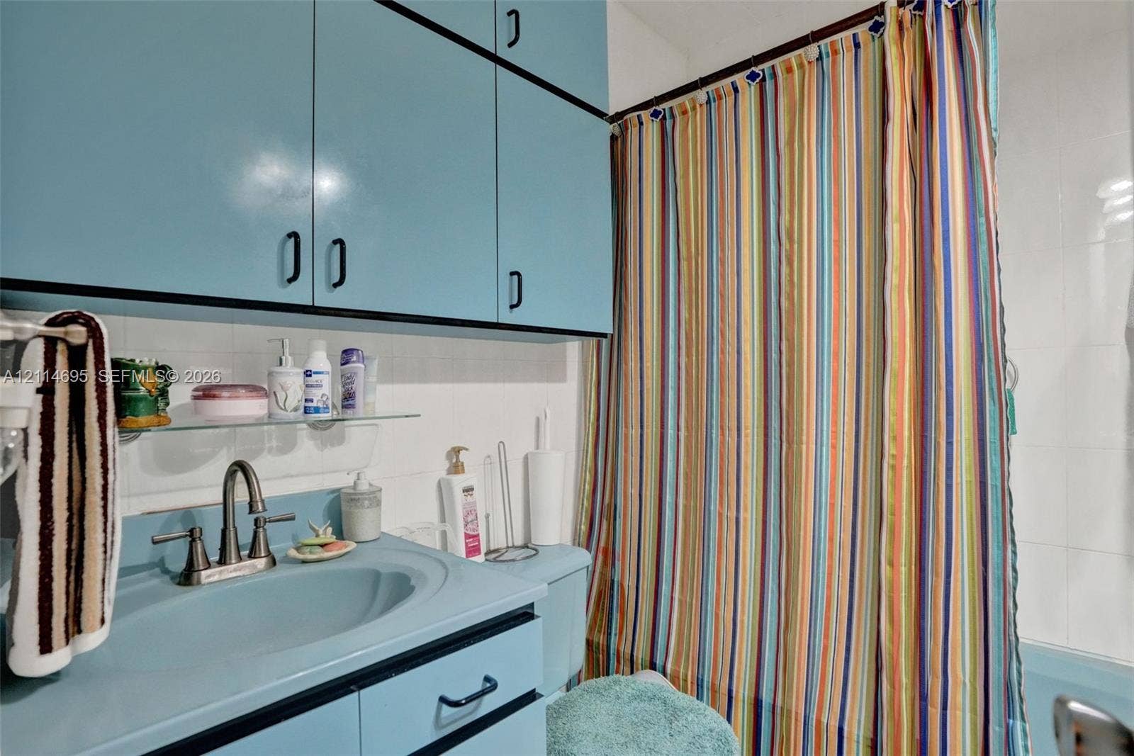 Built-in cabinetry featuring high-gloss blue finish, integrated vanity with matching molded basin, brushed-metal bridge faucet, and wall-mounted glass shelving