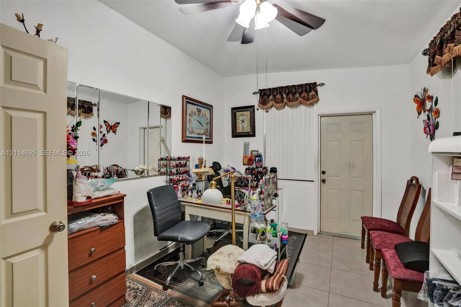 Room featuring tile flooring, a ceiling fan with light fixture, and a wall-mounted mirror