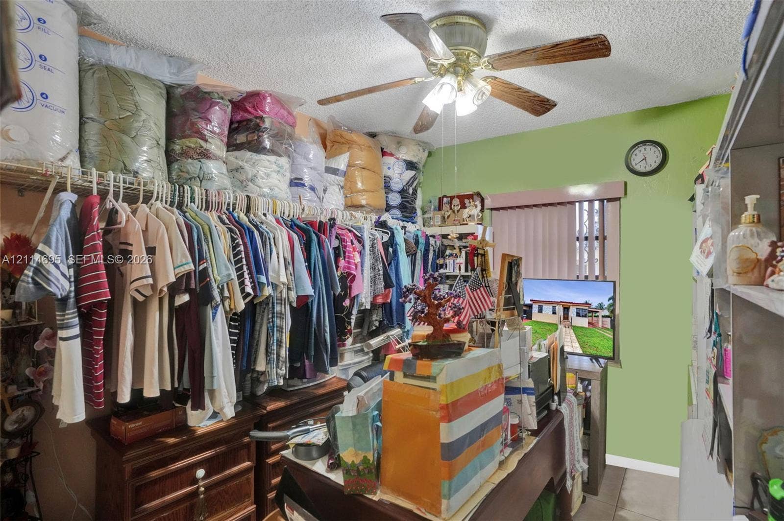 Wire shelving units, ceiling fan with integrated light fixture, and window with vertical blinds