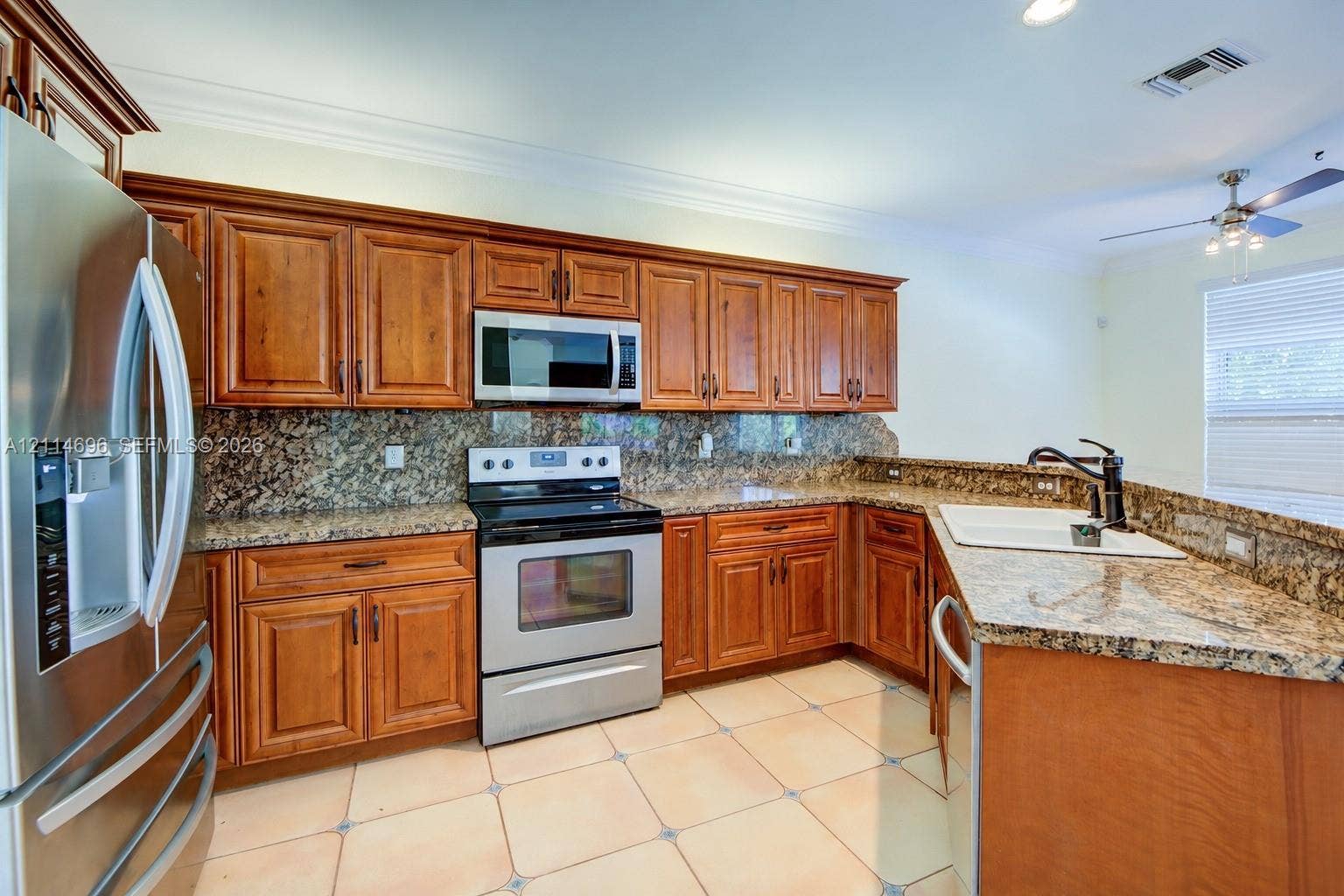 Kitchen featuring raised-panel wood cabinetry, granite countertops and backsplash, stainless steel appliances and tile flooring