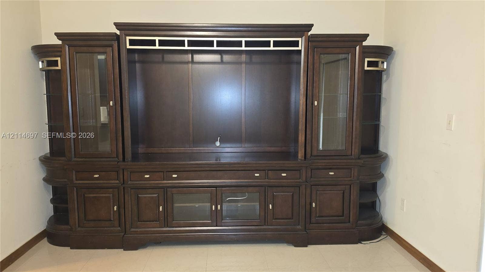121 SW 113th Avenue, #104-10, Sweetwater, Sweetwater, FL 33174 Built-in wall unit featuring dark-stained wood cabinetry, glass-paneled display doors, integrated shelving, and multi-drawer storage