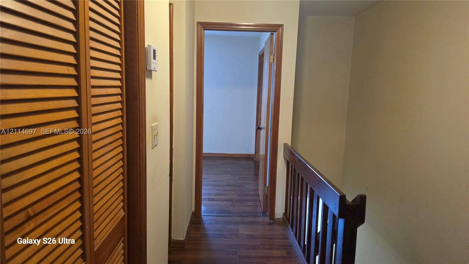 121 SW 113th Avenue, #104-10, Sweetwater, Sweetwater, FL 33174 Hallway featuring wood-finish flooring, wood-toned louvered closet doors, and a wood-railing staircase balustrade
