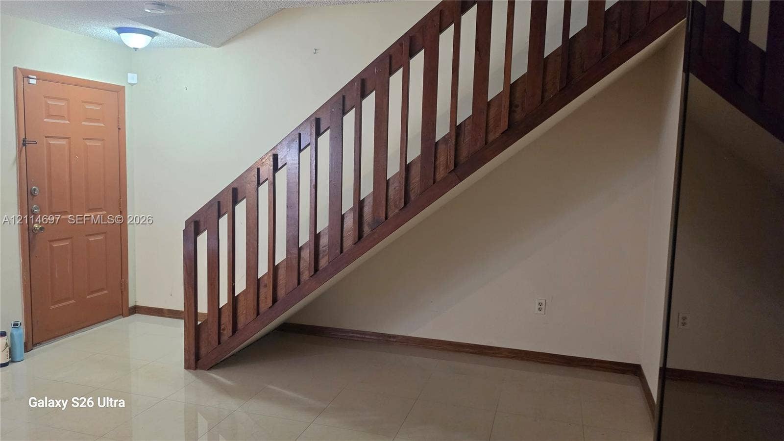 121 SW 113th Avenue, #104-10, Sweetwater, Sweetwater, FL 33174 Entrance featuring a solid-core door, high-gloss tile flooring, and a wood-slat staircase railing