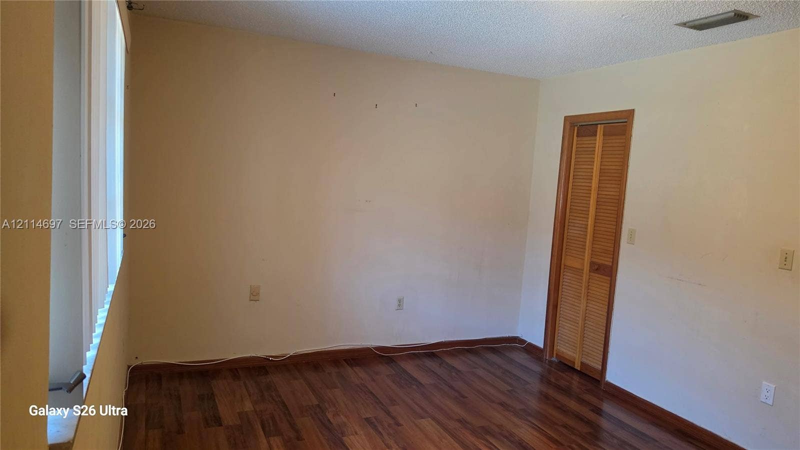 121 SW 113th Avenue, #104-10, Sweetwater, Sweetwater, FL 33174 Interior room featuring wood-finish flooring, vertical slat window blinds, and a built-in closet with louvered doors