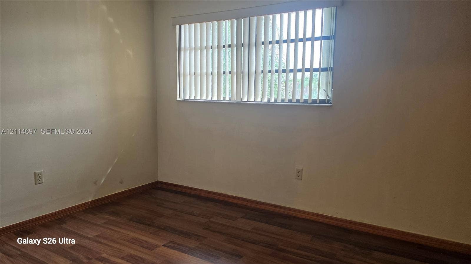 121 SW 113th Avenue, #104-10, Sweetwater, Sweetwater, FL 33174 Interior space featuring neutral-toned walls, wood-finish flooring, and a large horizontal window equipped with vertical blinds