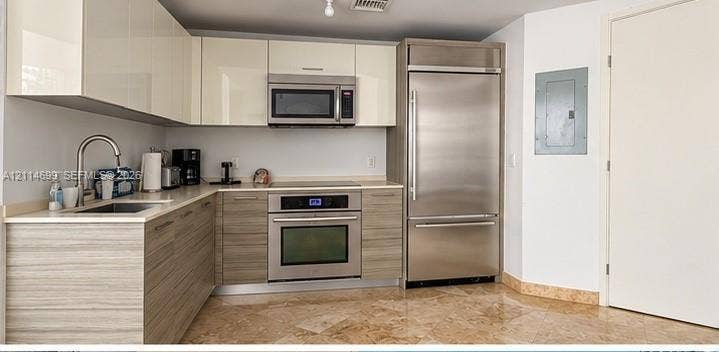 1300 Brickell Bay Drive, #3007, Miami, FL 33131 Kitchen featuring high-gloss upper cabinetry, wood-finish lower cabinetry, integrated stainless steel refrigerator, built-in wall oven with cooktop, and stone tile flooring