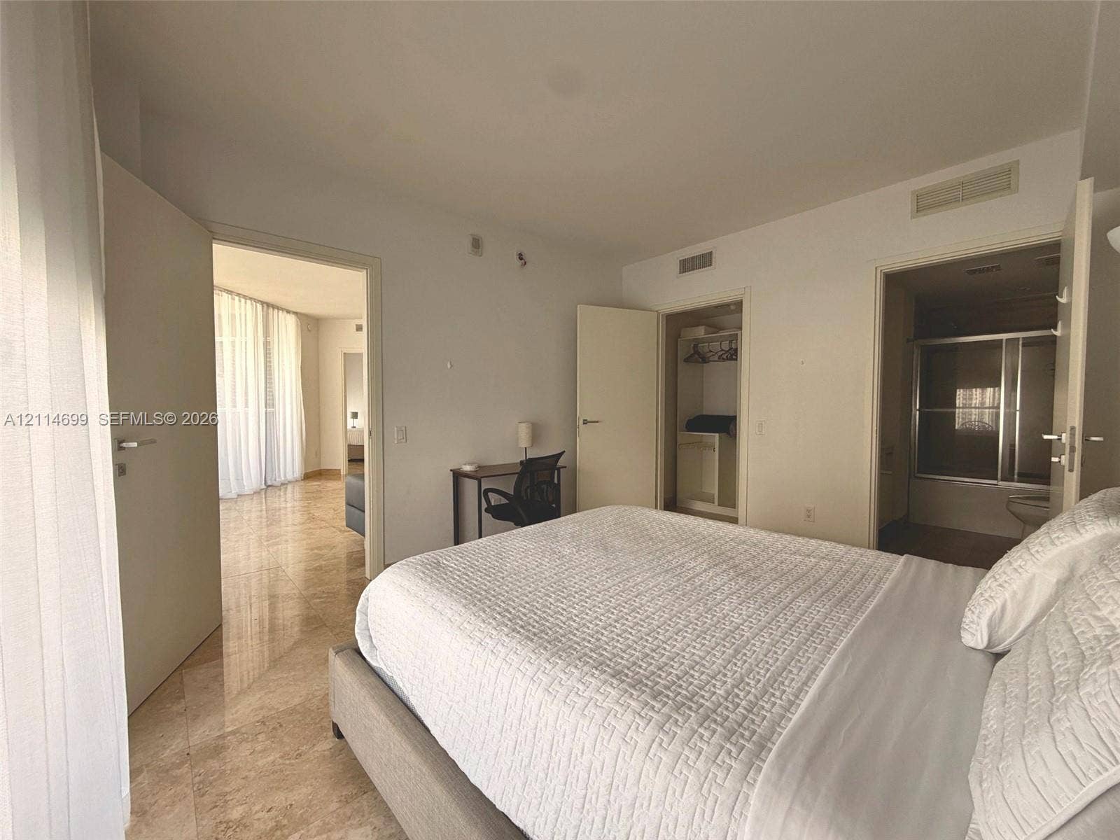 1300 Brickell Bay Drive, #3007, Miami, FL 33131 Spacious room featuring polished stone flooring, built-in closet cabinetry, and a private ensuite bathroom with a glass-enclosed shower