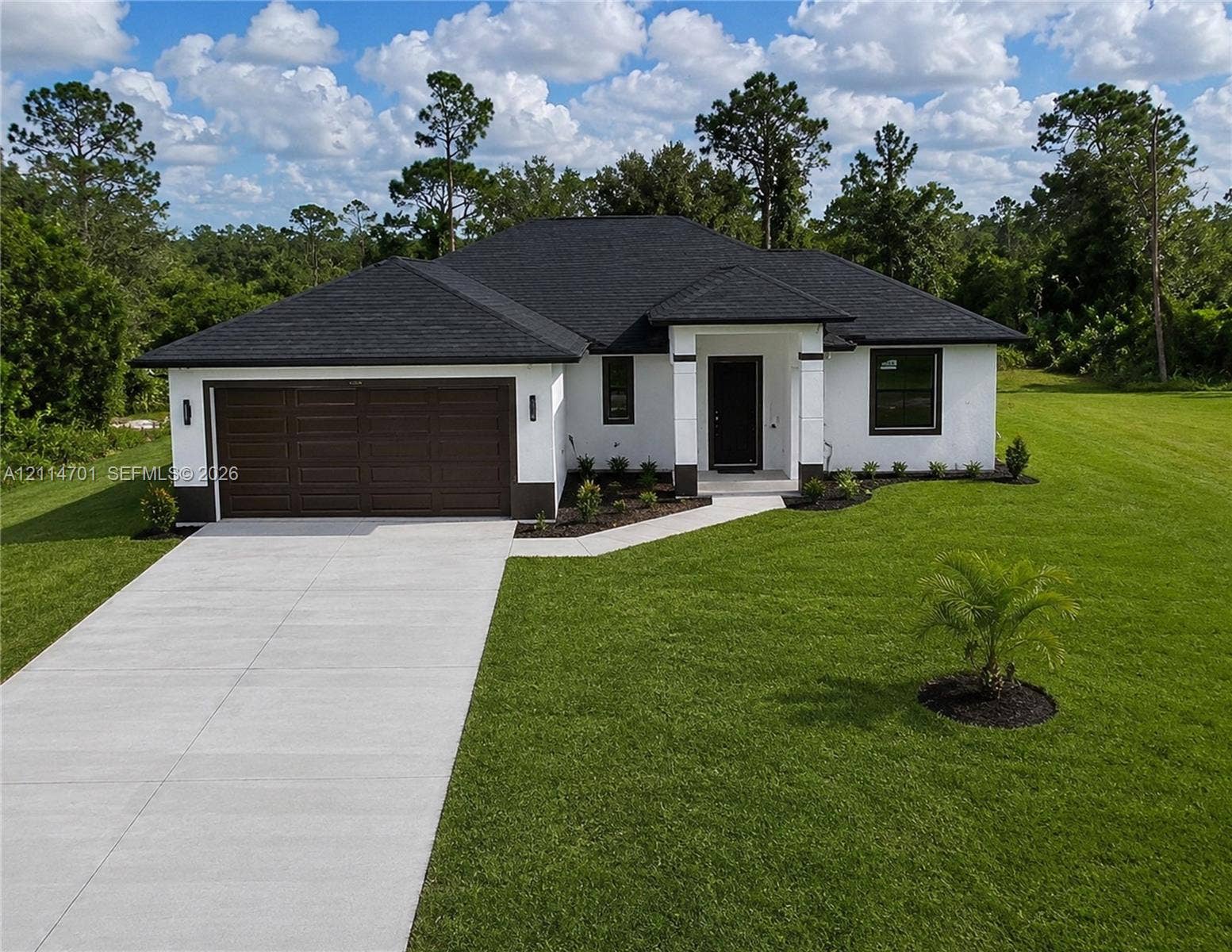 Single-story exterior featuring white stucco siding, a dark-toned shingle roof, an attached two-car garage, and a concrete driveway