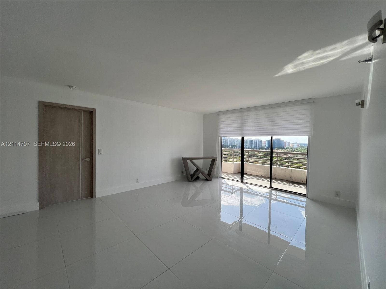 3300 NE 191st Street, #1405, Aventura, Aventura, FL 33180 Interior space featuring polished stone-finish flooring, floor-to-ceiling sliding glass doors, motorized window shades, and a wood-finish interior door