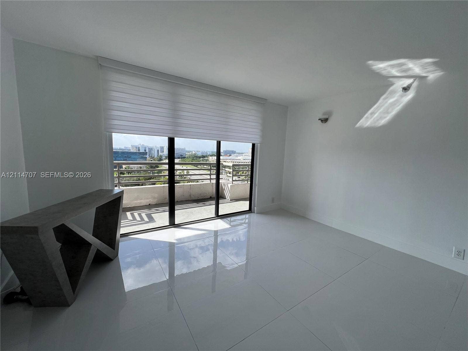 3300 NE 191st Street, #1405, Aventura, Aventura, FL 33180 Large-format tile flooring, wall-mounted lighting fixture, floor-to-ceiling sliding glass doors, and a private balcony with metal railing