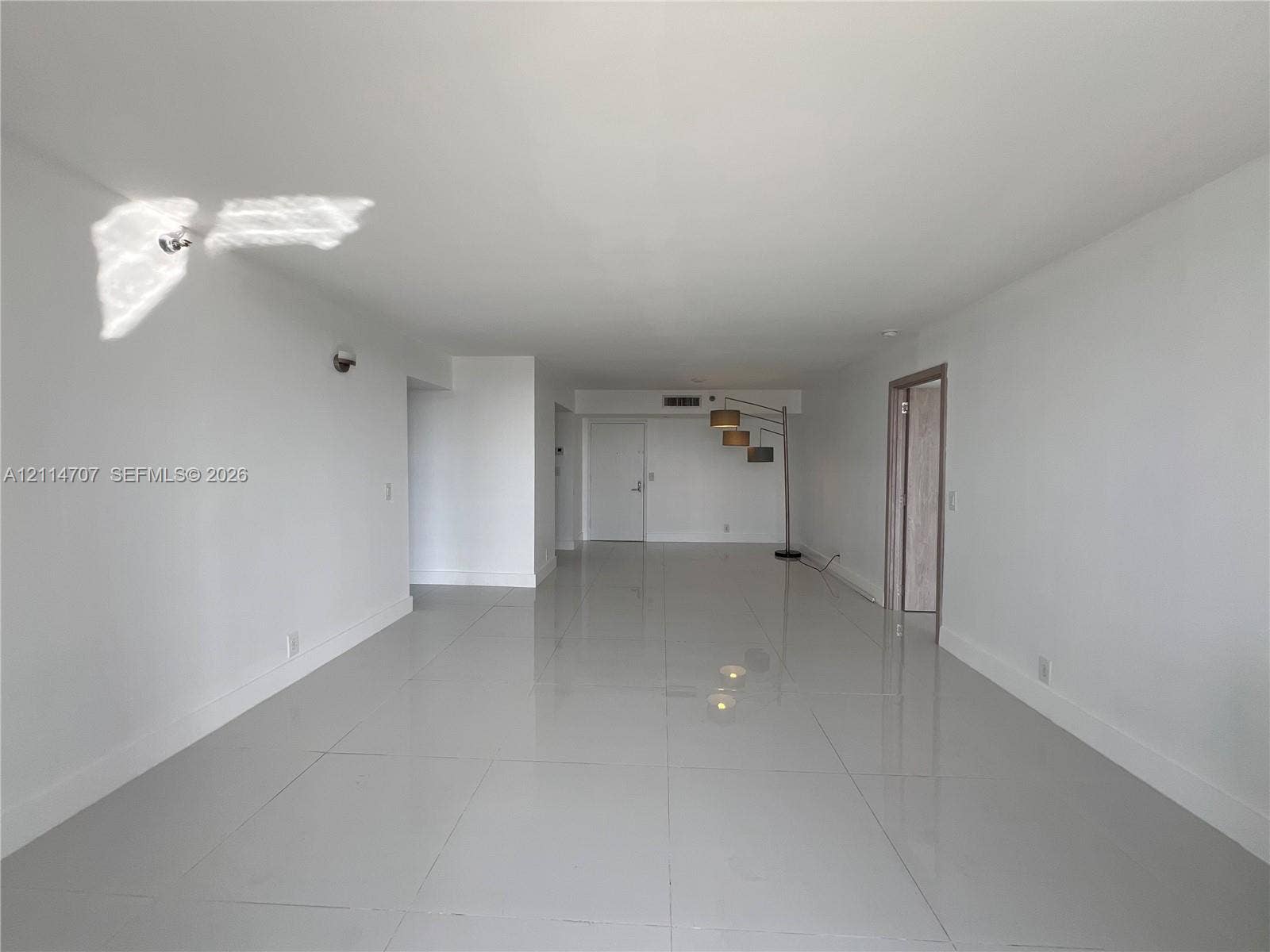 3300 NE 191st Street, #1405, Aventura, Aventura, FL 33180 Open-concept interior space featuring high-gloss tile flooring, smooth ceilings, and interior door frames with a natural wood finish