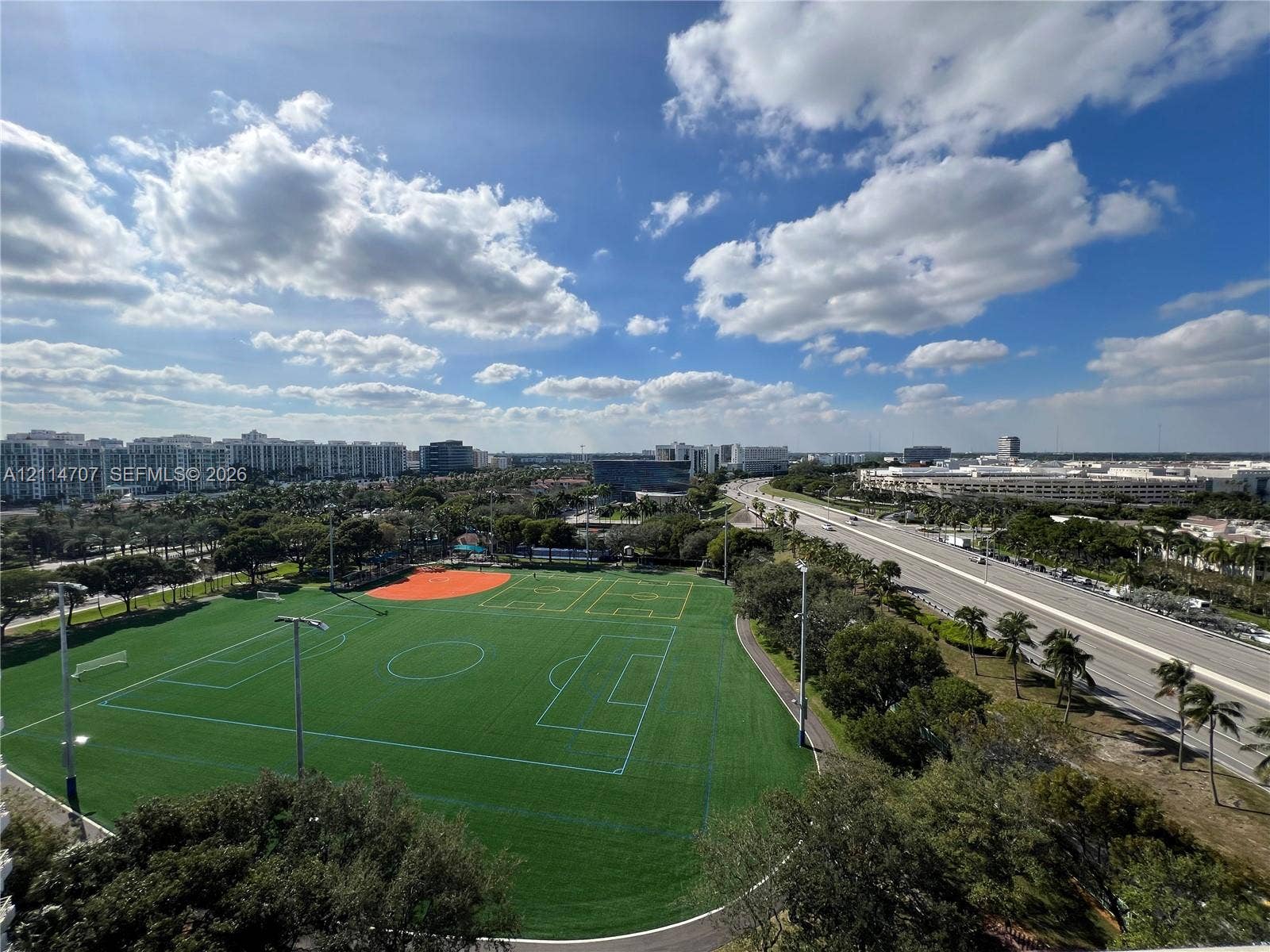 3300 NE 191st Street, #1405, Aventura, Aventura, FL 33180 Elevated aerial perspective featuring a multi-sport turf field with integrated markings, perimeter lighting, and paved walking paths