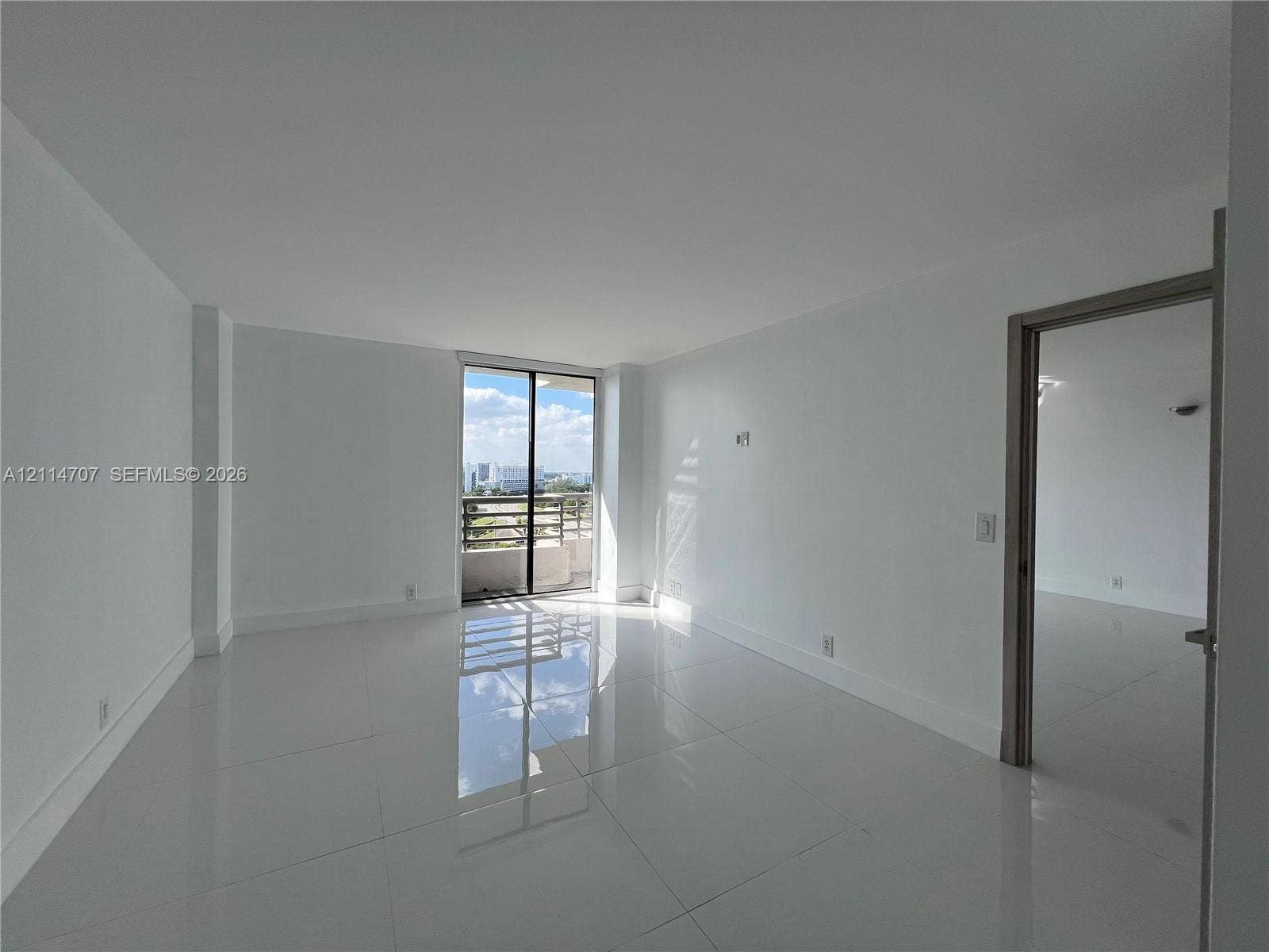 3300 NE 191st Street, #1405, Aventura, Aventura, FL 33180 Neutral-toned interior featuring large-format tile flooring, smooth wall finishes, and a sliding glass door providing external access