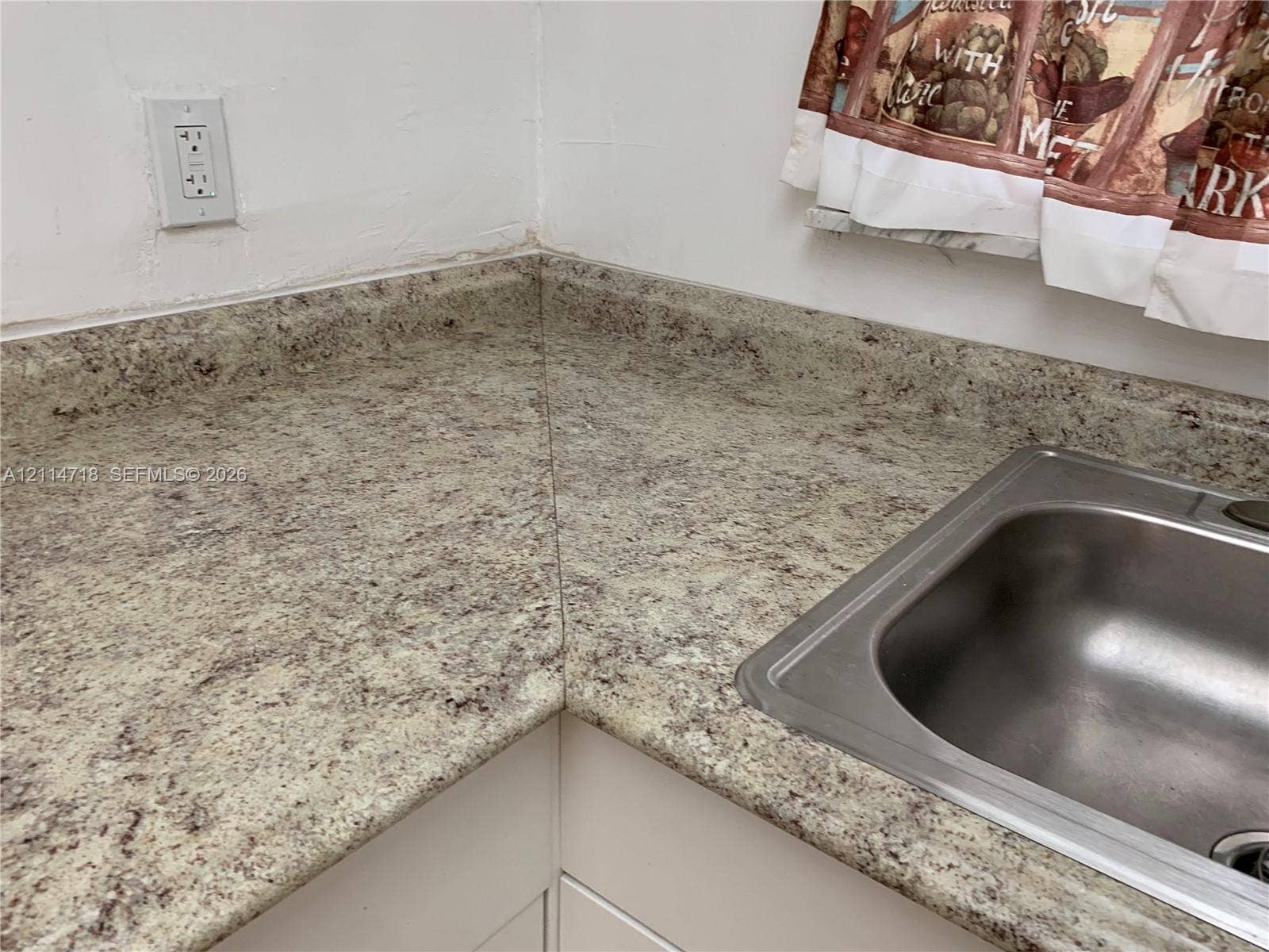 Speckled stone-finish countertop with an integrated backsplash and a stainless steel drop-in sink