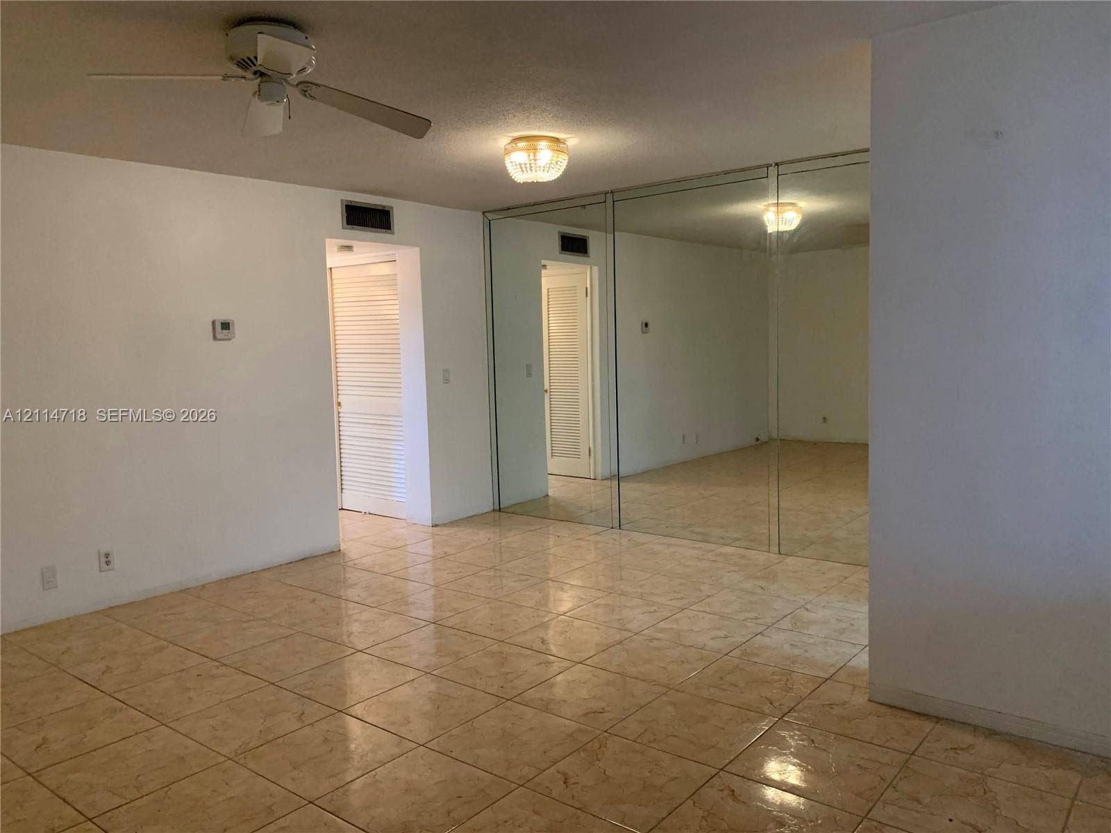 Ceramic tile flooring, full-wall mirrored closet doors, ceiling fan with light kit, and flush-mount ceiling fixture