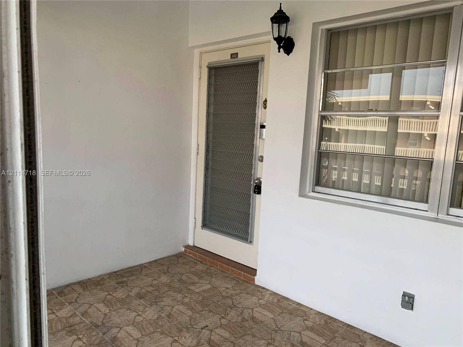 Entryway featuring a stone-tile floor, metal screen door, and exterior wall-mounted light fixture