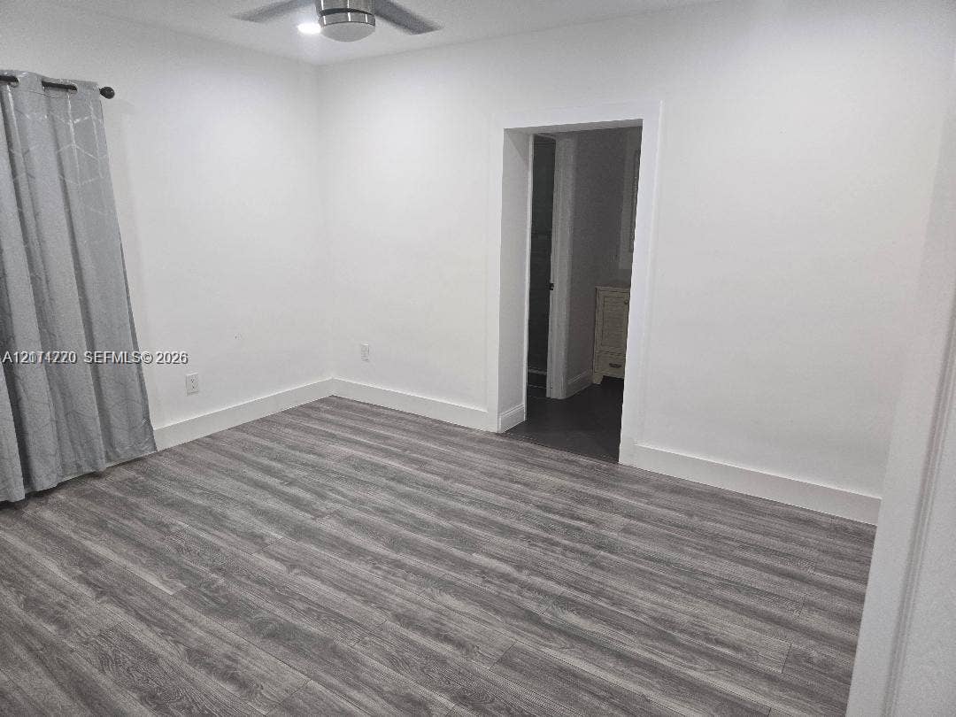 Interior space featuring wood-finish flooring, white walls, and a ceiling-mounted light fixture