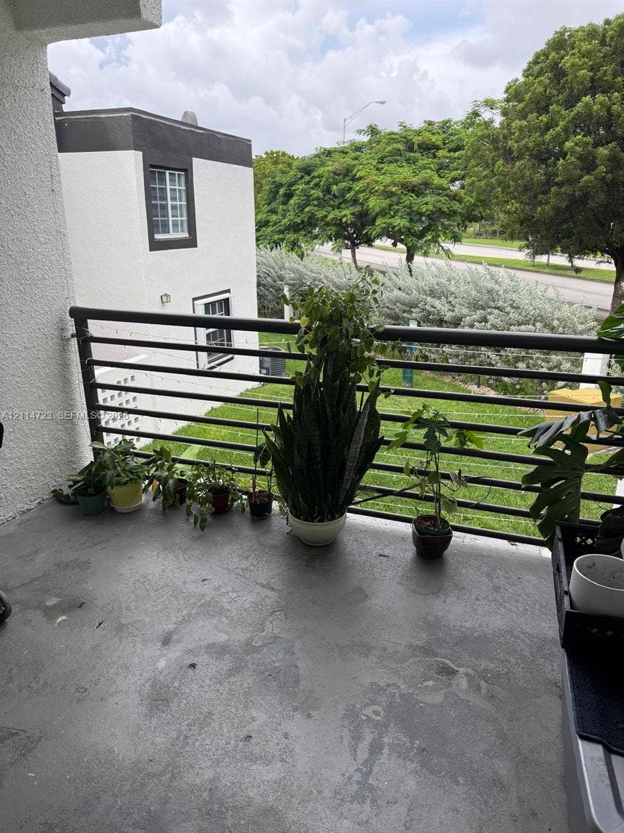 Covered balcony featuring concrete flooring and a horizontal metal railing