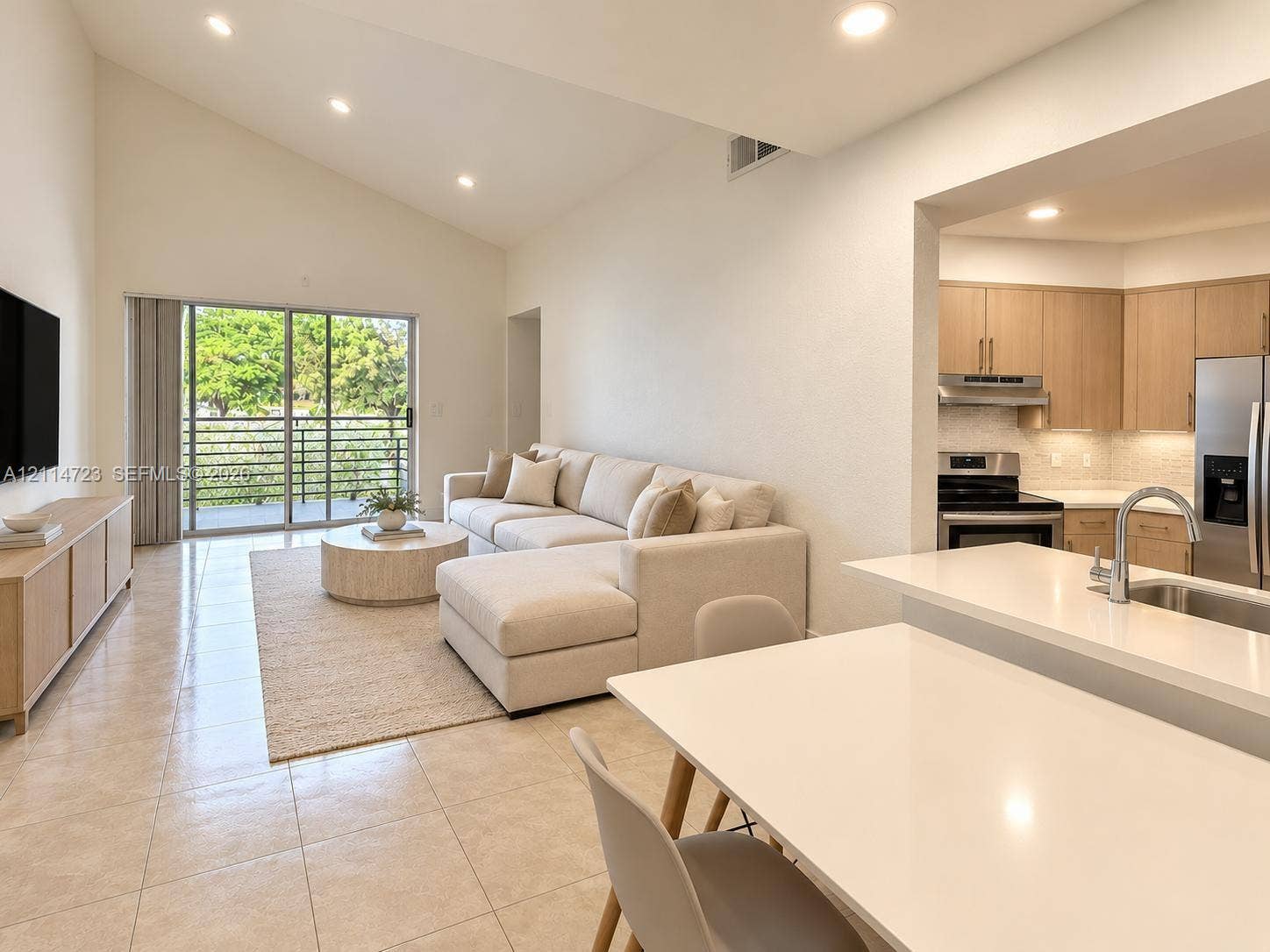 Vaulted ceilings, neutral tile flooring, sliding glass balcony door, quartz countertops, and stainless steel kitchen appliances