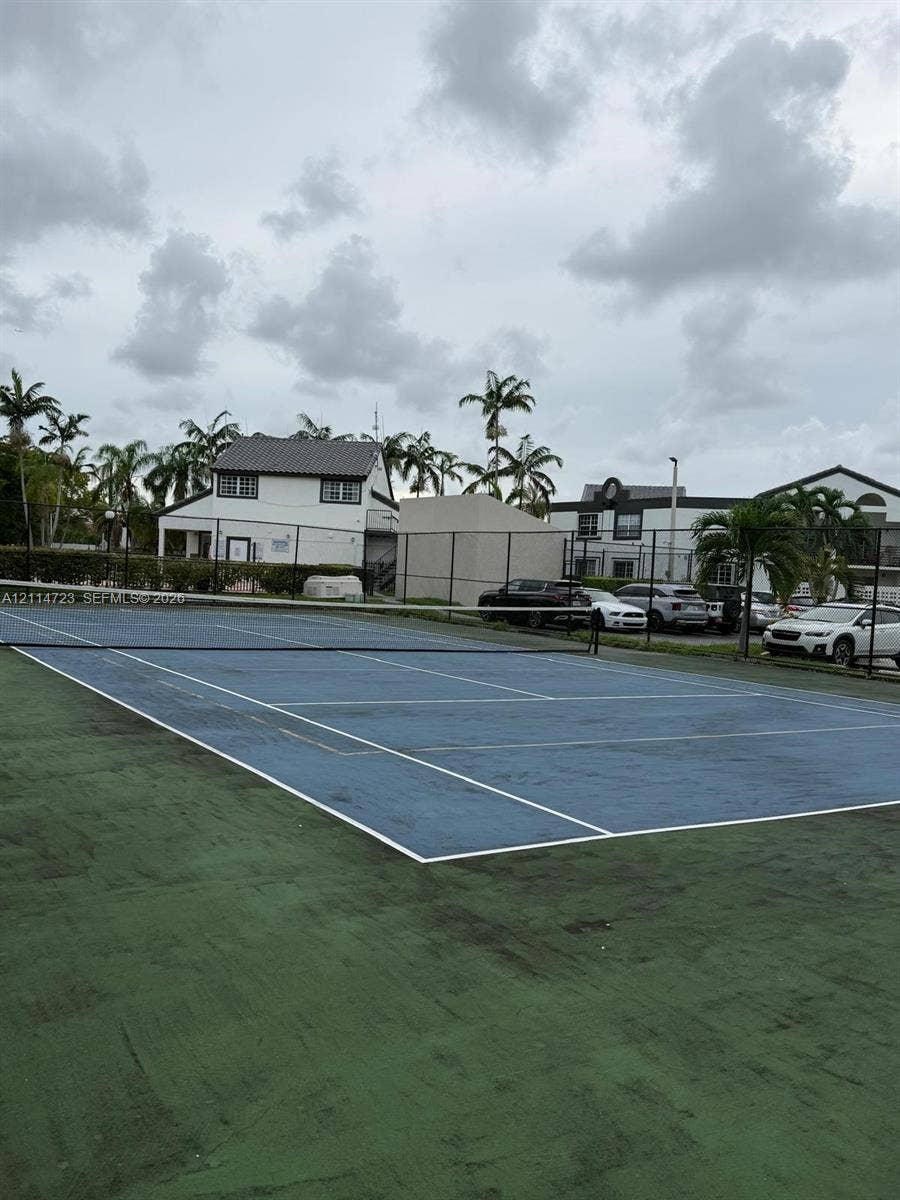 Tennis court featuring a blue surface with white boundary markings and a perimeter chain-link fence