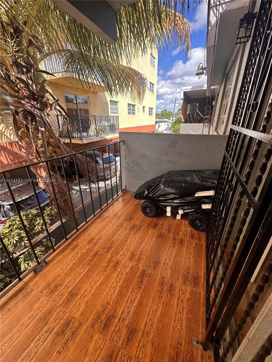 1285 W 26th Place, #202, Hialeah, Hialeah, FL 33010 Balcony featuring wood-finish flooring, black metal railings, and attached exterior lighting