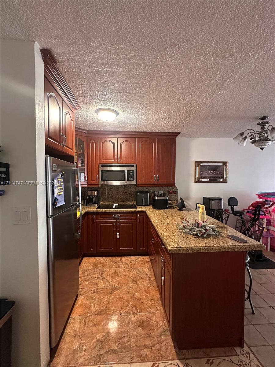 1285 W 26th Place, #202, Hialeah, Hialeah, FL 33010 Kitchen featuring stained wood cabinetry, stone-surface countertops, tile flooring, and integrated stainless steel appliances