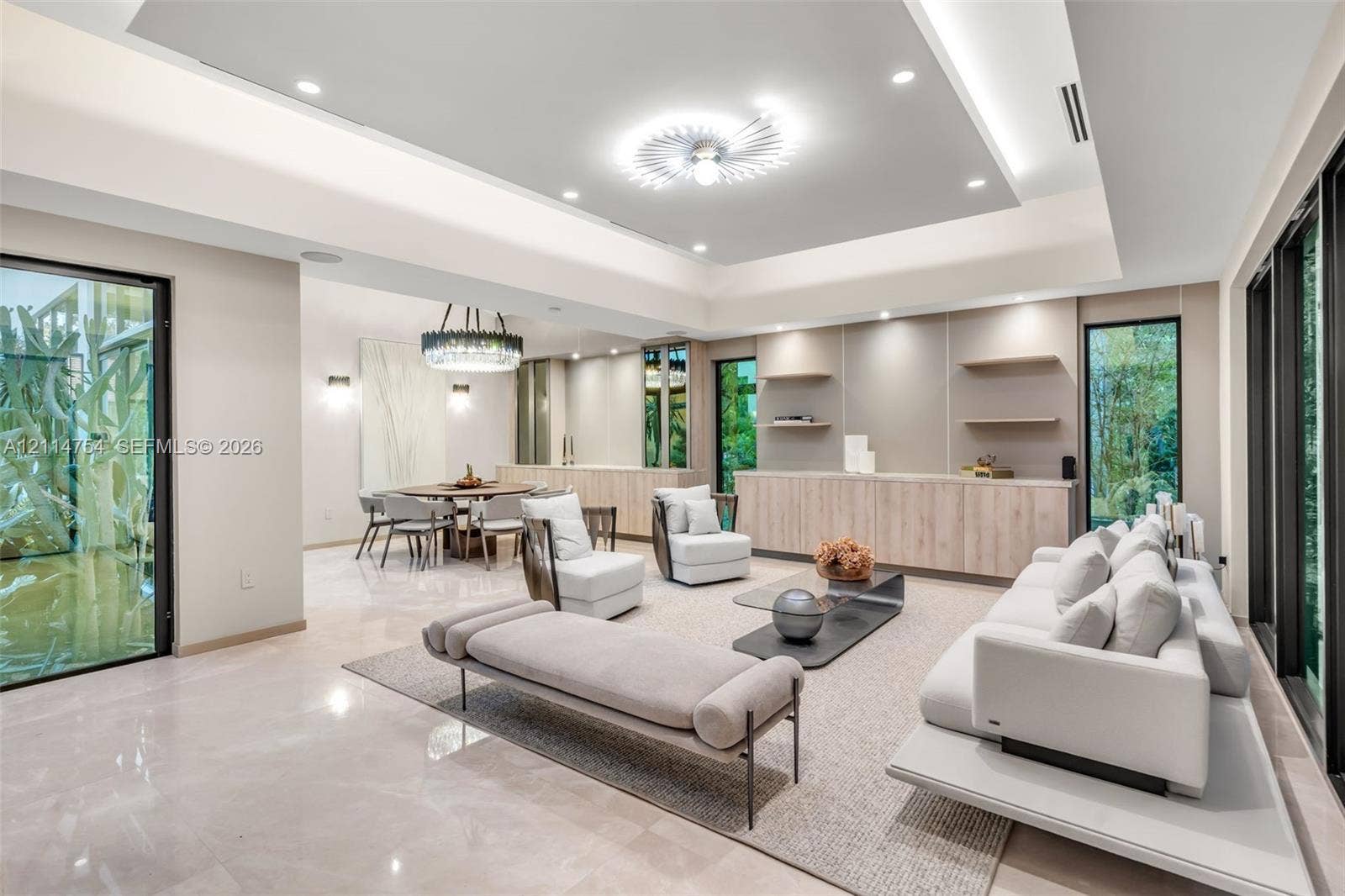 6731 SW 64th Avenue, South Miami, FL 33143 Tray ceiling with recessed lighting, integrated wood-finish cabinetry with stone countertop, floating wall shelves, large-format tile flooring, and floor-to-ceiling glass sliding doors